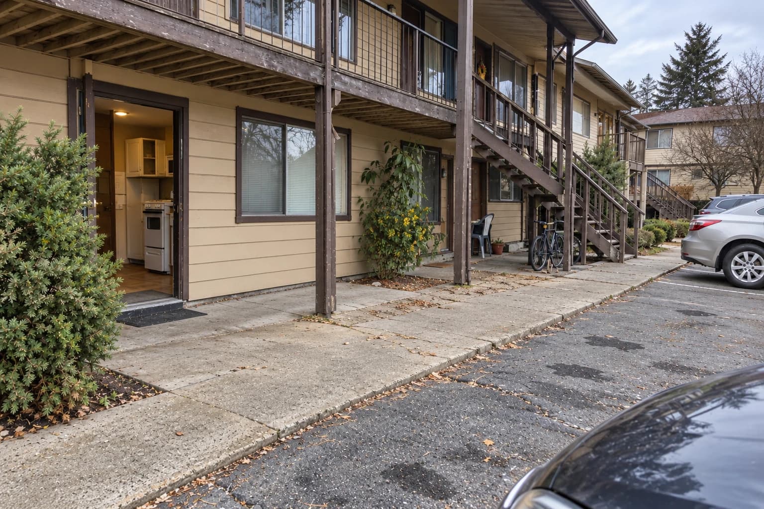 Generated after example: the same occupied apartment property from a separate camera view, with clear paths, weathered stairs, parked cars and residents' belongings unchanged